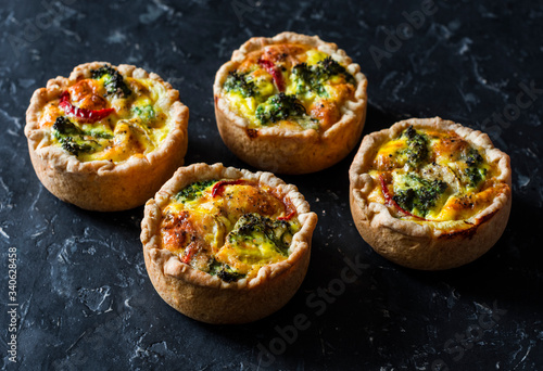 Broccoli, ham, cheddar pies on dark background, top view. Delicious appetizers, snack, tapas