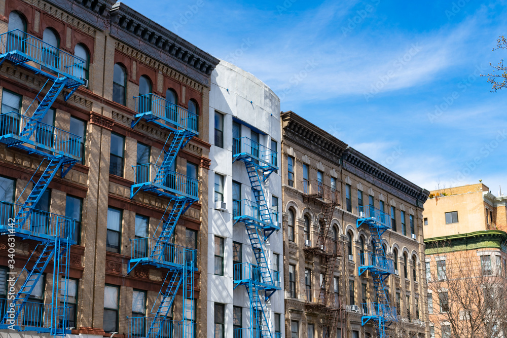 Row of Old Buildings with Blue Fire Escapes in Harlem of New York City