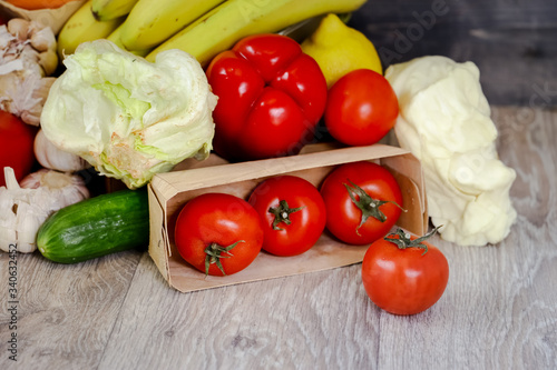 Against the background of a light countertop, tomatoes, cucumber, red pepper, garlic, iceberg salad.