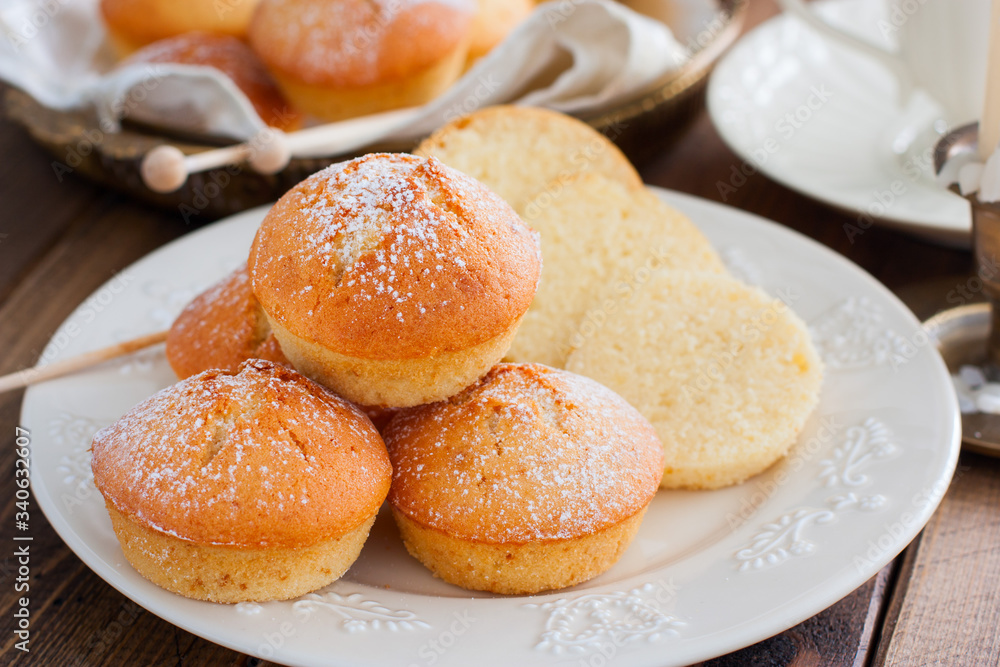 Homemade vanilla muffins sprinkled with icing sugar, selective focus Homemade vanilla muffins sprinkled with icing sugar, selective focus