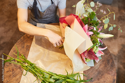 Hände von Florist beim Blumen in Papier wickeln photo