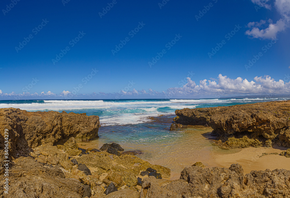 The clear blue waters of the Pacific Ocean splashing onto the rocky shoreline of