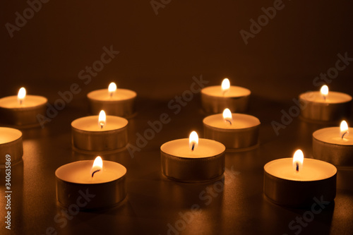 Fire flames of small candles, shadowy, catholic and christian scene © paulaguicub