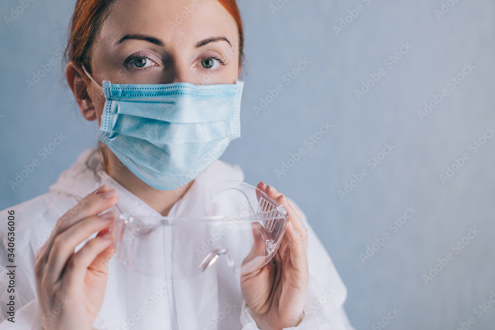 Female doctor puts on safety glasses, close-up of face.