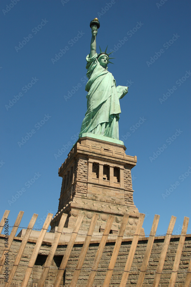 Obraz premium New York City (Manhattan)/ USA-5th September 2010: The panorama of the statue of liberty overlooks the dark blue sky and the skyscrapers of Manhattan to show the freedom of the United State.