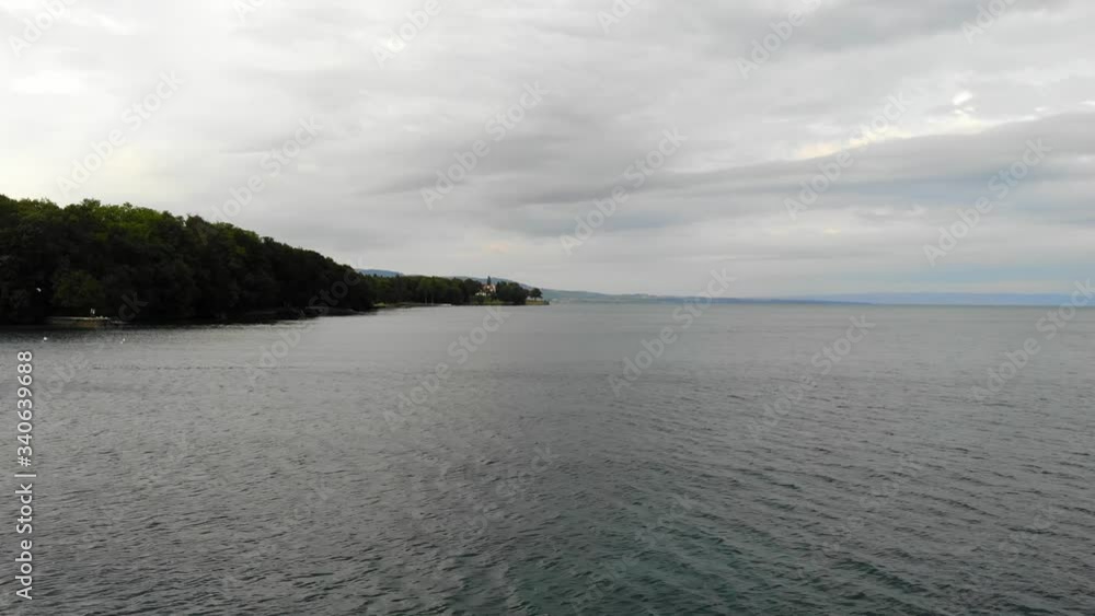 Drone Aerial Moving Over Lake Lac-Léman Near Geneva Switzerland With Cloudy Sky and Forest In the Background Drone Aerial Moving Over Lake Lac-Léman Near Geneva Switzerland With Cloudy Sky and Forest In the Background