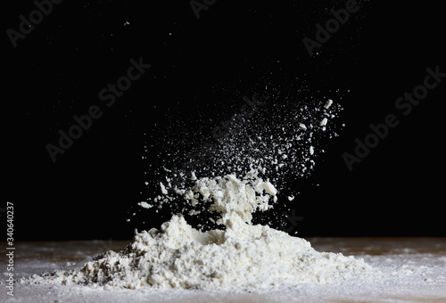 фотографія kitchen view with falling flour on the table for making dough