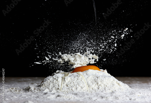 Fotografía kitchen process on a dark background with an egg falling on the flour when prepa