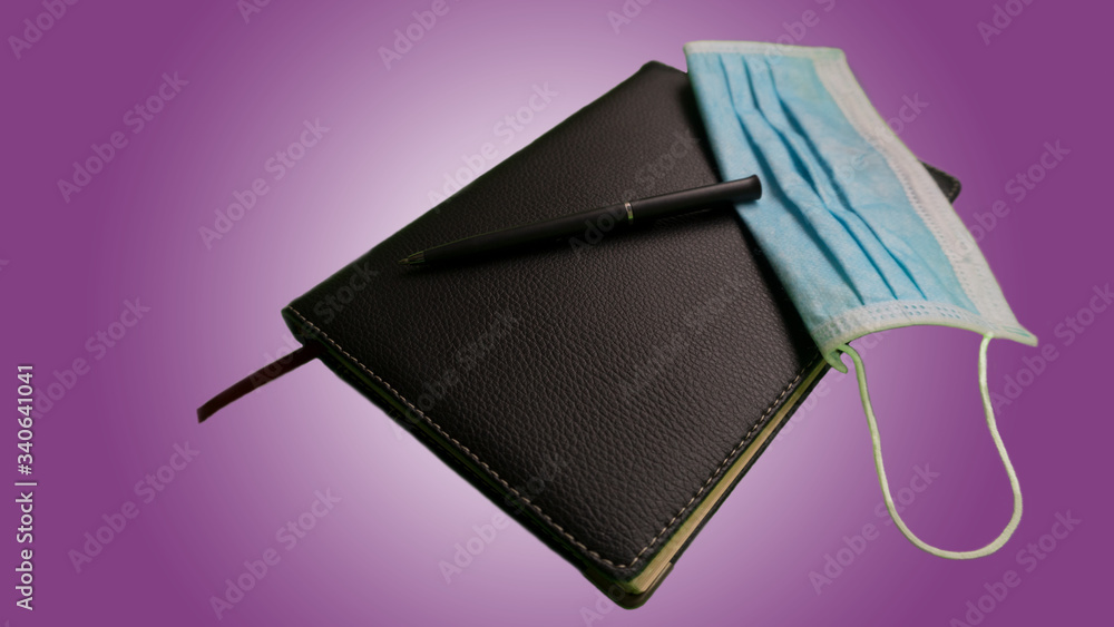 Agenda and pen with mask-Telework coronavirus, COVID work meeting, purple background Agenda and pen with mask-Telework coronavirus, COVID work meeting, purple background