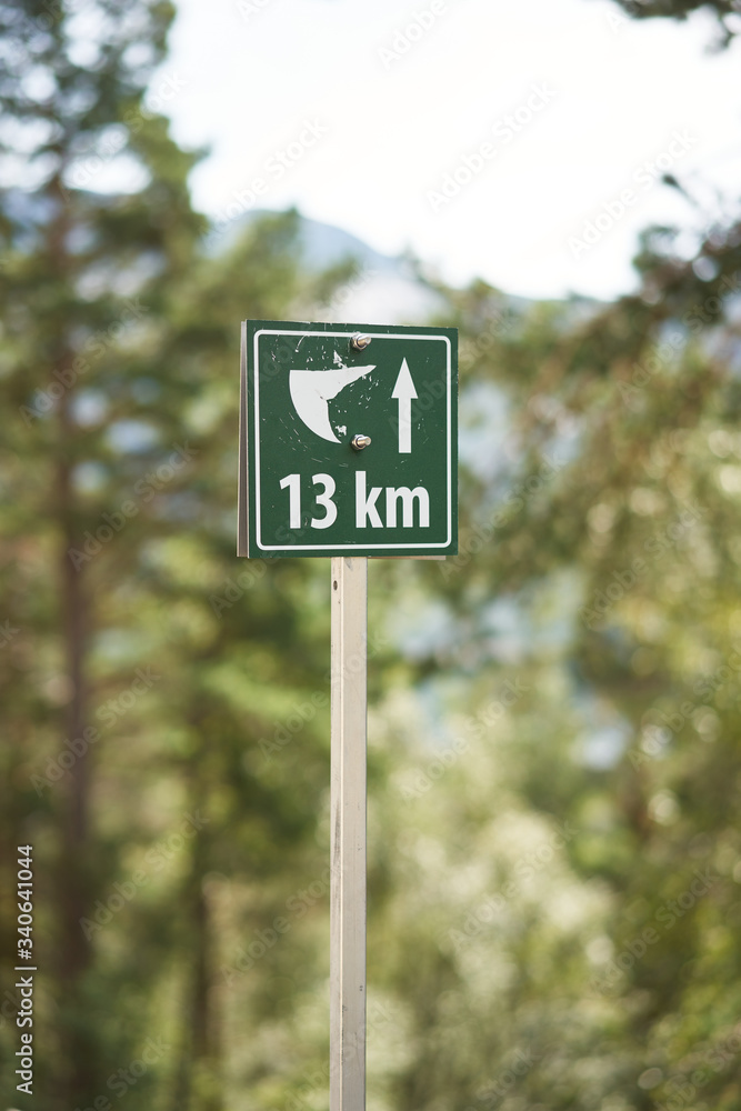 Hiking tourist closeup rout sign to Trolltunga rock with distance, Norway