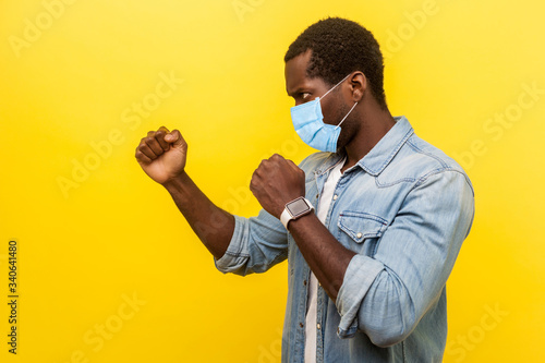 Billede på lærred Side view portrait of confident man with surgical medical mask standing in defensive posture with clenched fists attack, ready to fight, attack
