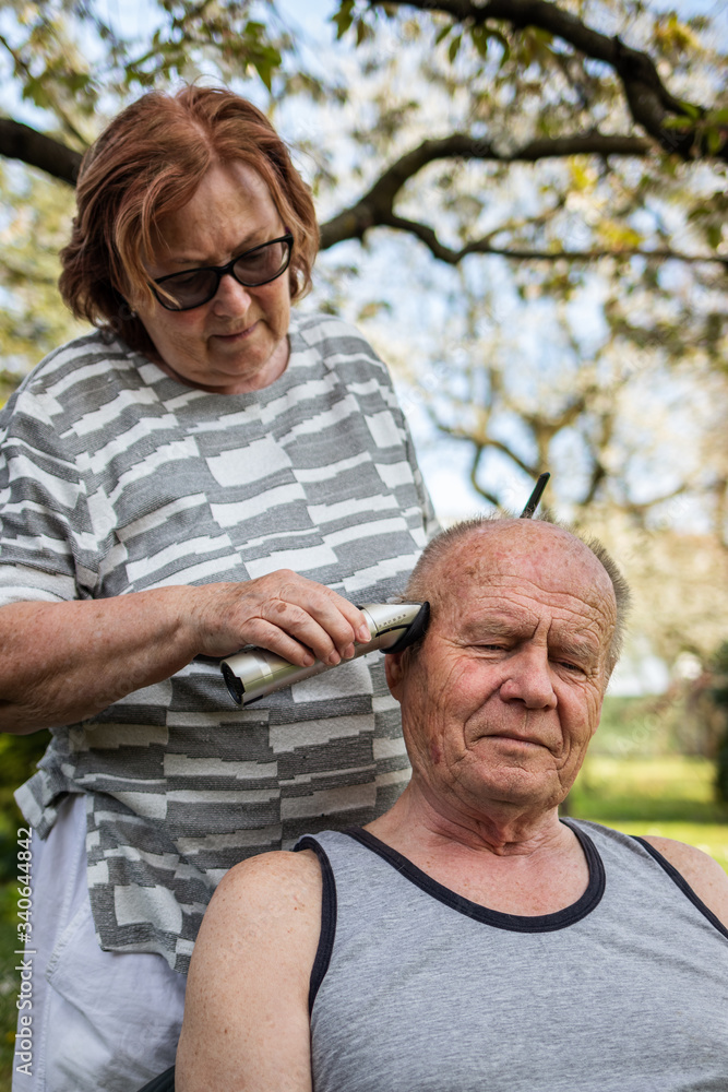 Stay home, stay safe and positive and take care of yourself within the same family during coronavirus lockdown. Senior couple is doing haircut each other at backyard Stay home, stay safe and positive and take care of yourself within the same family during coronavirus lockdown. Senior couple is doing haircut each other at backyard