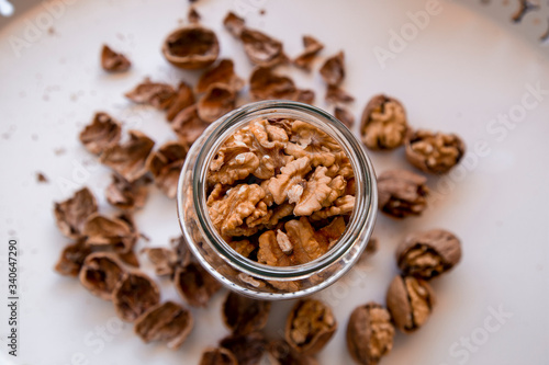 Whole walnuts in a jar. Walnuts on a white cutting board