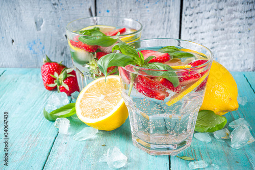 Strawberries and basil lemonade. Summer cold iced cocktail recipe, with fresh strawberry, lemon and basil leaves, wooden background copy space