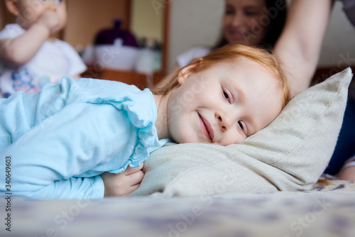 A redheaded girl lies on a pillow and smiles