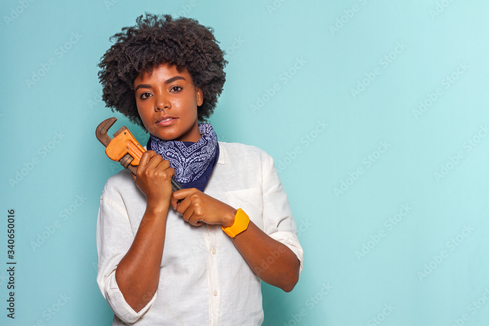 Black young woman with black power hair using a stillson key Black young woman with black power hair using a stillson key