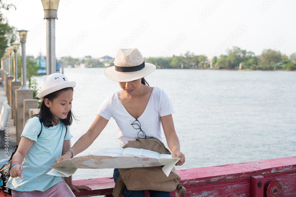 looking away. Outdoor portrait of two girls traveling around new place and searching beautiful sights. wonderful inspired curly woman in hat holding pretty daughter and town by the river map... looking away. Outdoor portrait of two girls traveling around new place and searching beautiful sights. wonderful inspired curly woman in hat holding pretty daughter and town by the river map...