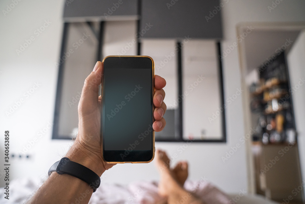 Smartphone in a male hand against the background of the interior of a bedroom house. Watching the news.