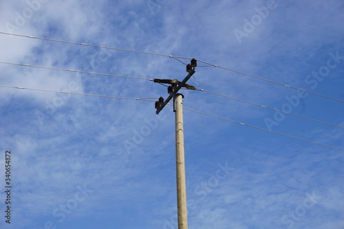 Telekommunikationsmast, Holzmast mit Stromleitung, isolierter Mast vor blauen Himmel