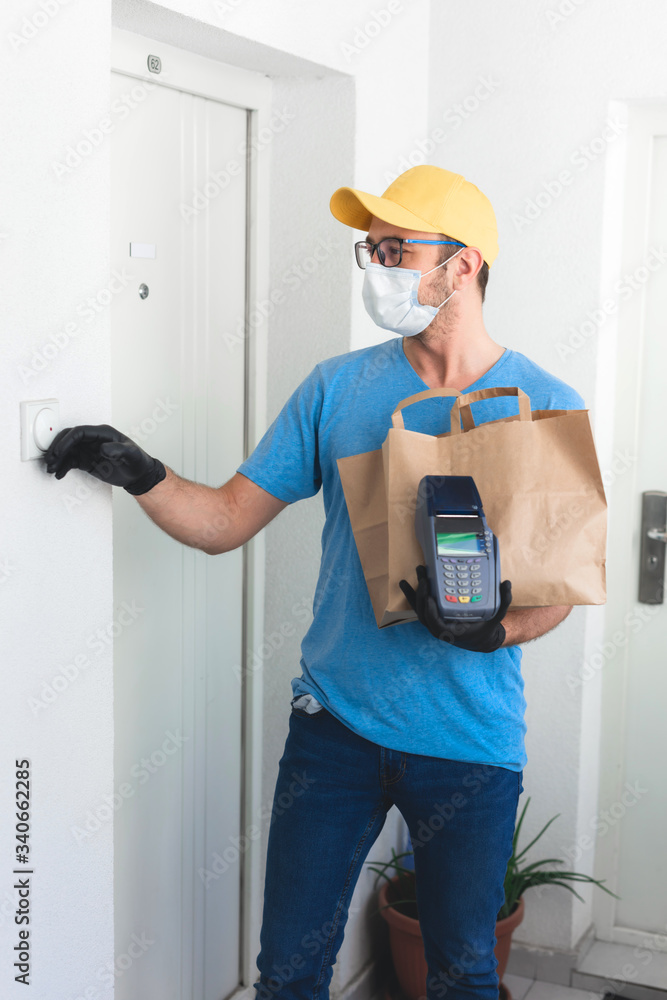 Delivery guy with protective mask holding box / bag with groceries and POS for contactless payment. Delivery guy with protective mask holding box / bag with groceries and POS for contactless payment.