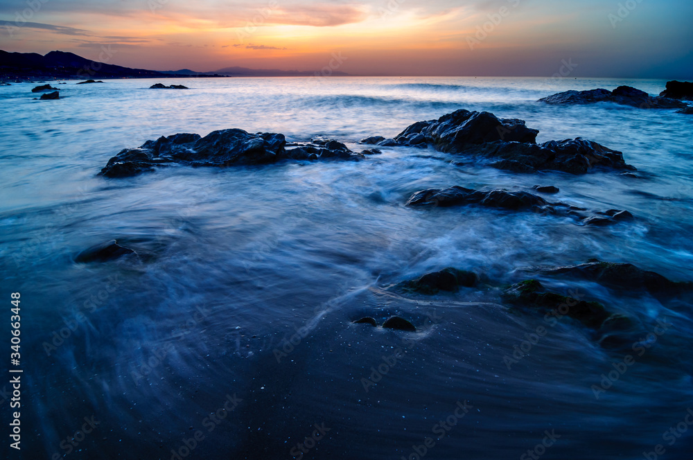 Sun, Sea and Rocky Sunrise. Impressive landscape of a beach with long exposure
