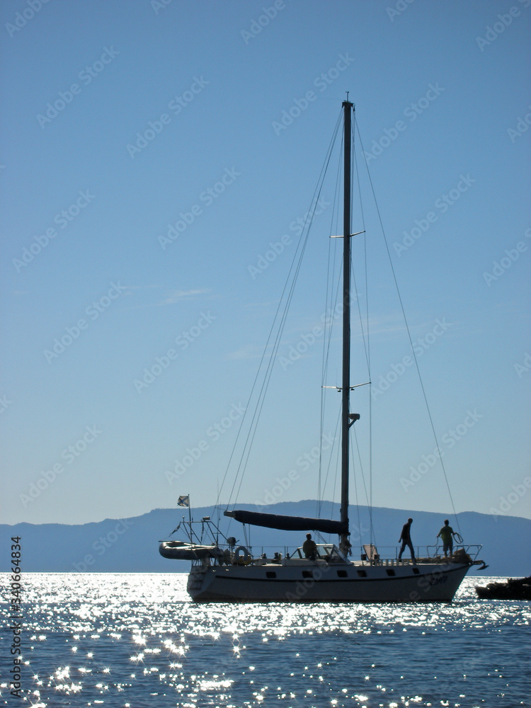 yacht sailboat in the sea silhouettes of men, lake Baikal, calm Sunny weather, glare on the water