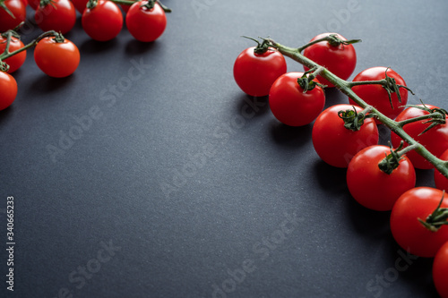 cherry tomatoes on a vine on dark background (ID: 340665233)