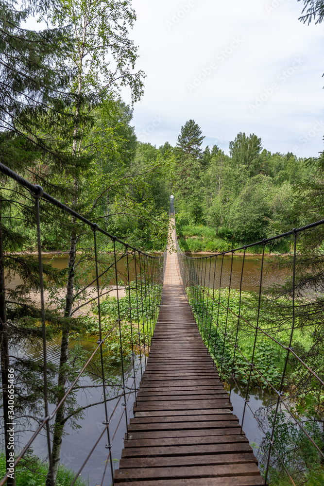 Suspension bridge over the Serga river in Deer streams national Park. Sverdlovsk region, Ural, Russia. Suspension bridge over the Serga river in Deer streams national Park. Sverdlovsk region, Ural, Russia.