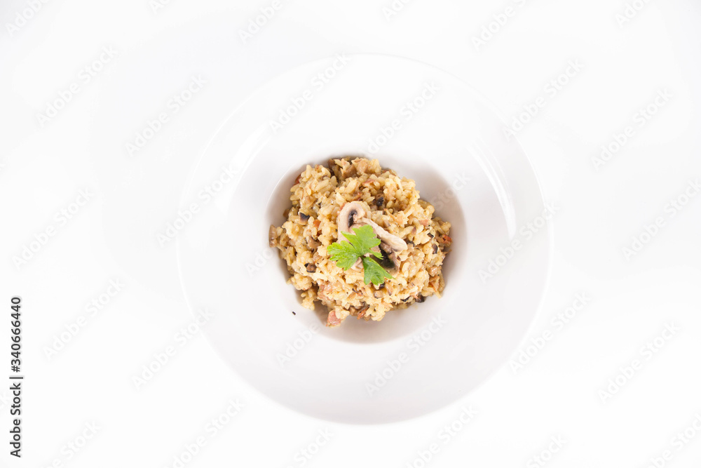 Risotto with button mushroom and bacon decorated with parsley on a plate on a white background Risotto with button mushroom and bacon decorated with parsley on a plate on a white background