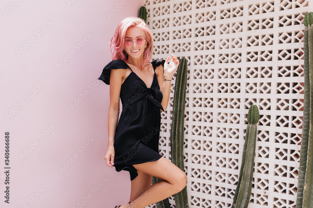Foto Blissful pink-haired girl standing on one leg near cactus