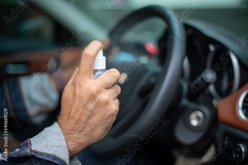 Asian man using spray alcohol to clean the car for coronavirus protection