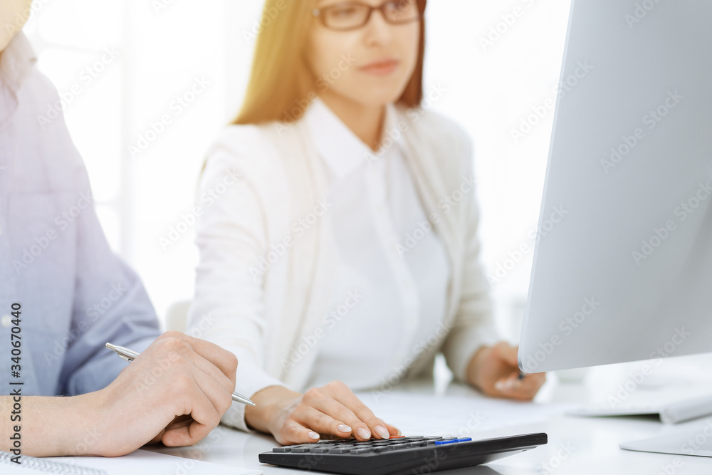 Fototapeta premium Bookkeeper checking balance with calculator, close-up of hands. Tax and audit concepts