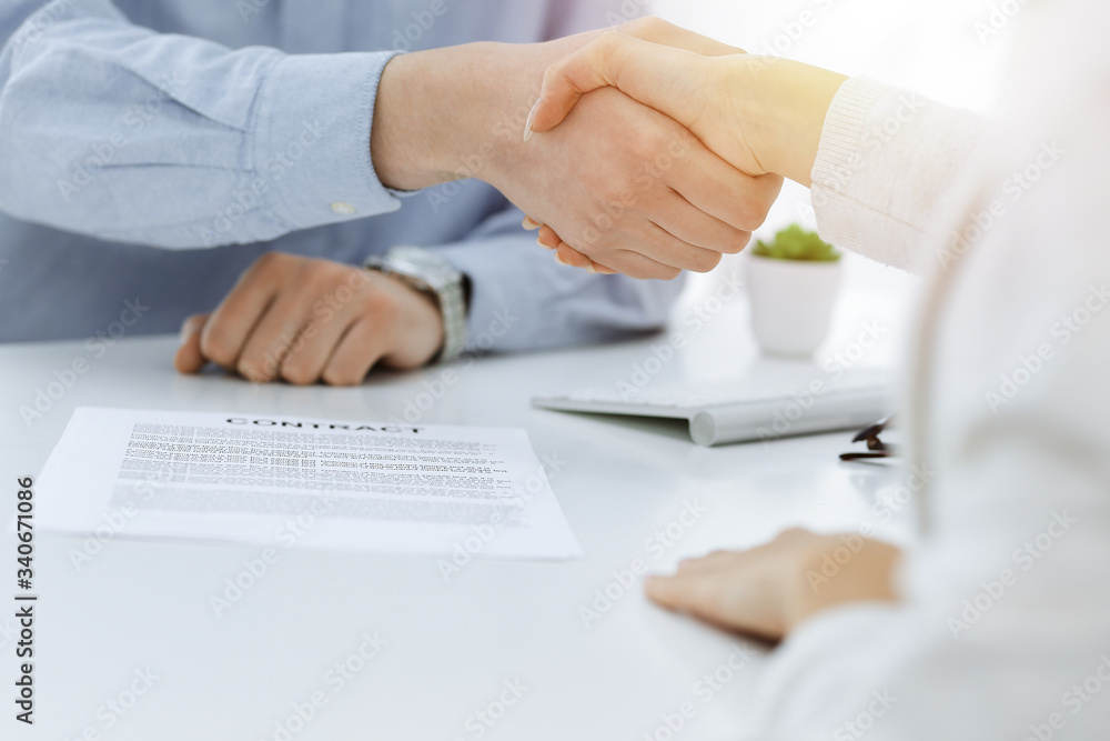 Casual dressed businessman and woman shaking hands after contract signing in sunny office. Handshake concept Casual dressed businessman and woman shaking hands after contract signing in sunny office. Handshake concept
