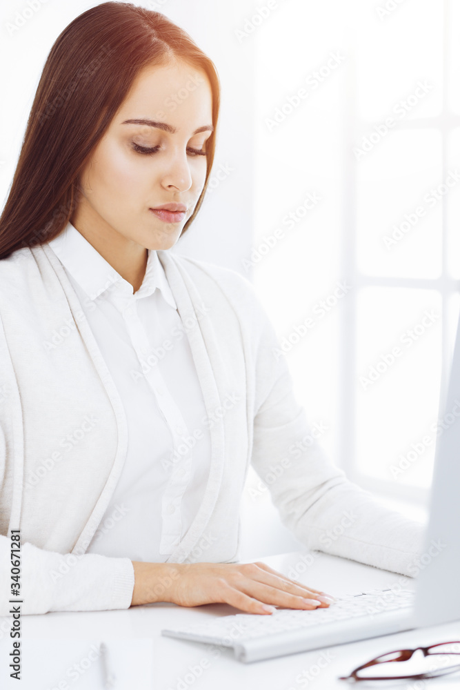 Business woman sitting and working with computer in white office. Student girl studying or secretary making report. Success concept Business woman sitting and working with computer in white office. Student girl studying or secretary making report. Success concept