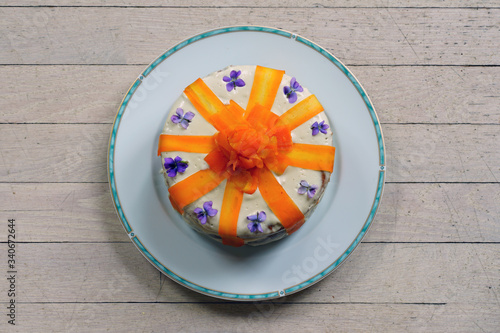 Vegan carrot cake with candied carrot ribbons and fresh violet flowers
