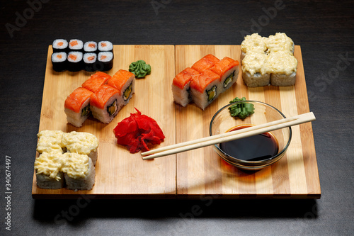 Tasty and delicious hot and cold sushi rolls on the table. Different sushi - rolls with sauce on the board of Japanese cuisine. photo