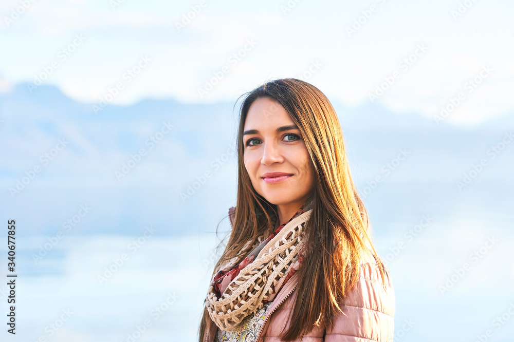 Outdoor portrait of beautiful young woman relaxing by the lake
