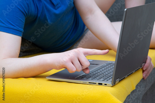 A man is sitting on the sofa at a laptop. Engaged in work on deleting over the Internet.