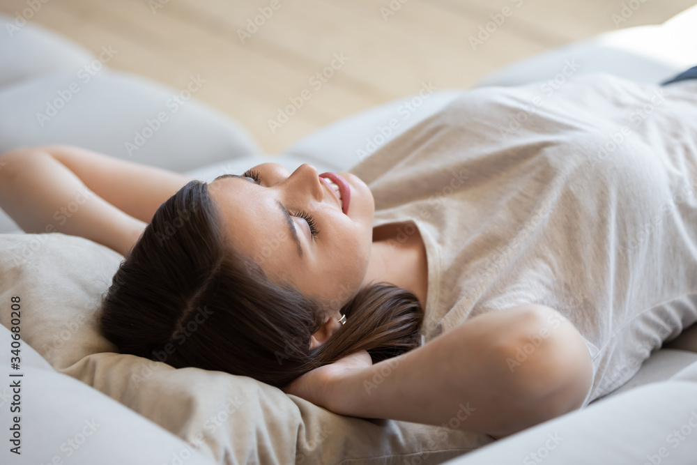 Close up satisfied happy woman with hands behind head relaxing and lying on comfortable sofa during break at home. Smiling attractive girl resting after house work done closed eyes, daydreaming. Close up satisfied happy woman with hands behind head relaxing and lying on comfortable sofa during break at home. Smiling attractive girl resting after house work done closed eyes, daydreaming.