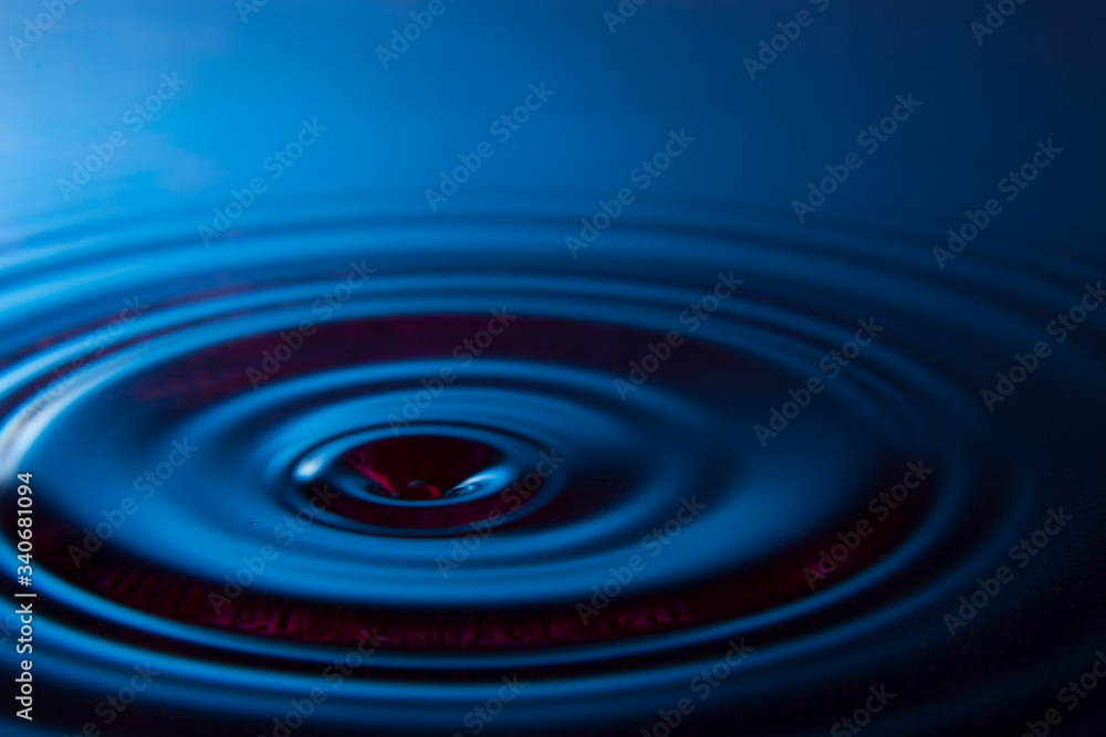 drop falling into blue calm water drop falling into blue calm water
