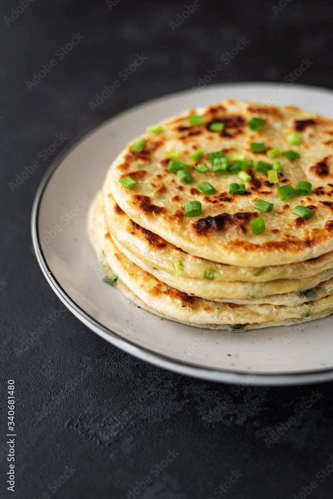 Chinese green onion pancakes on a black background. Stack of fried green onion pancakes. Dark photo