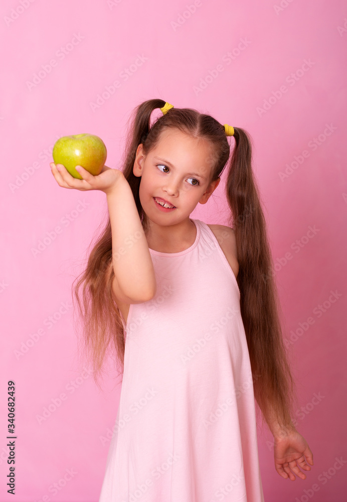 A little girl with a green Apple in her hands smiles sweetly A little girl with a green Apple in her hands smiles sweetly