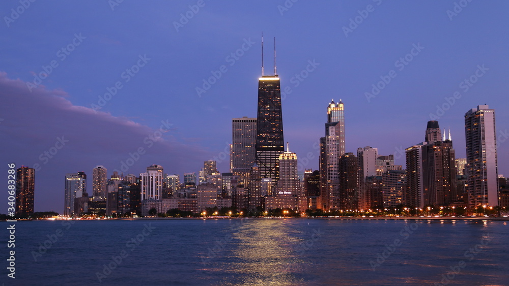 Chicago city urban skyscraper with John Hancock Center at night at downtown lakefront illuminated with Lake Michigan viewed from North Avenue Beach