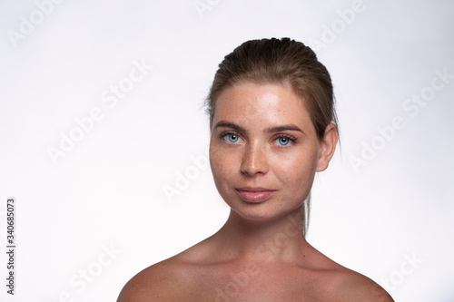 Beautiful girl with freckles shows emotions in front of the camera on a white background