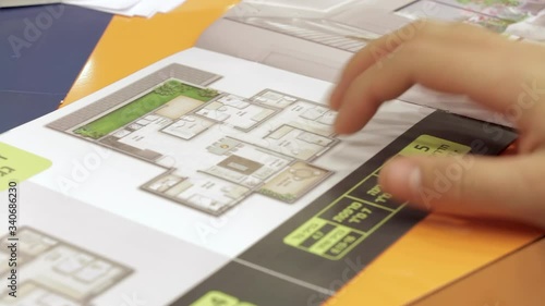 Israeli man looking at real estate information brochure. Close up on his hand. The hebrew words Dirot Emcha