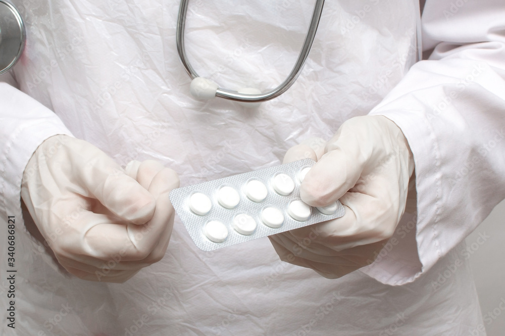 Doctor woman in a medical coat and gloves holds pills in her hands. Pills in the hands of a doctor close-up.