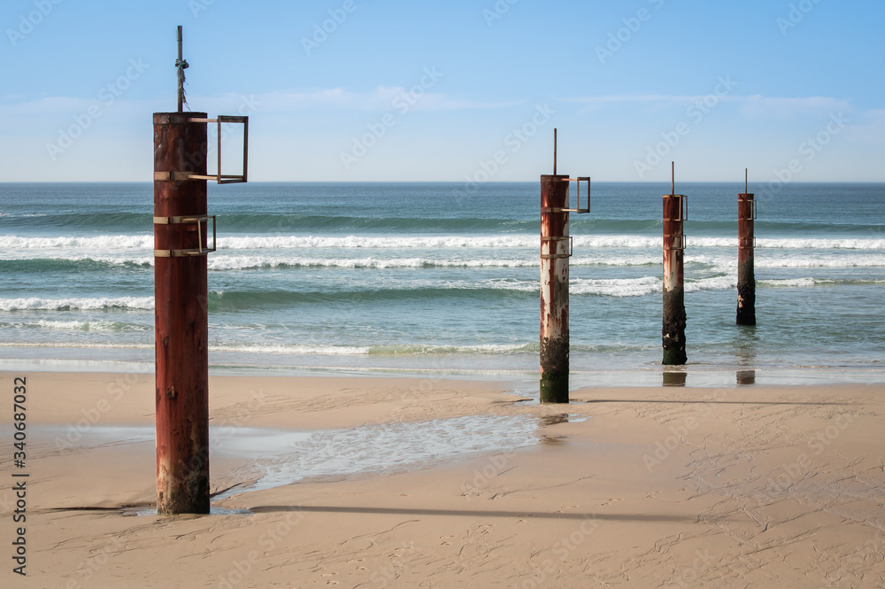 Pylônes rouillés sur la plage au bord de l'océan en été