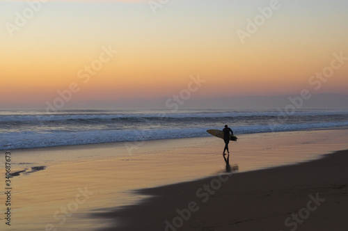 Silhouette de surfeur face au coucher de soleil sur l'océan