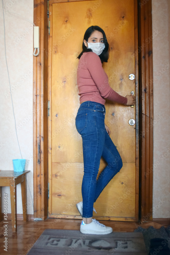 young woman with face mask leaning against door