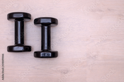 two small black dumbbells lie on the light floor of the room